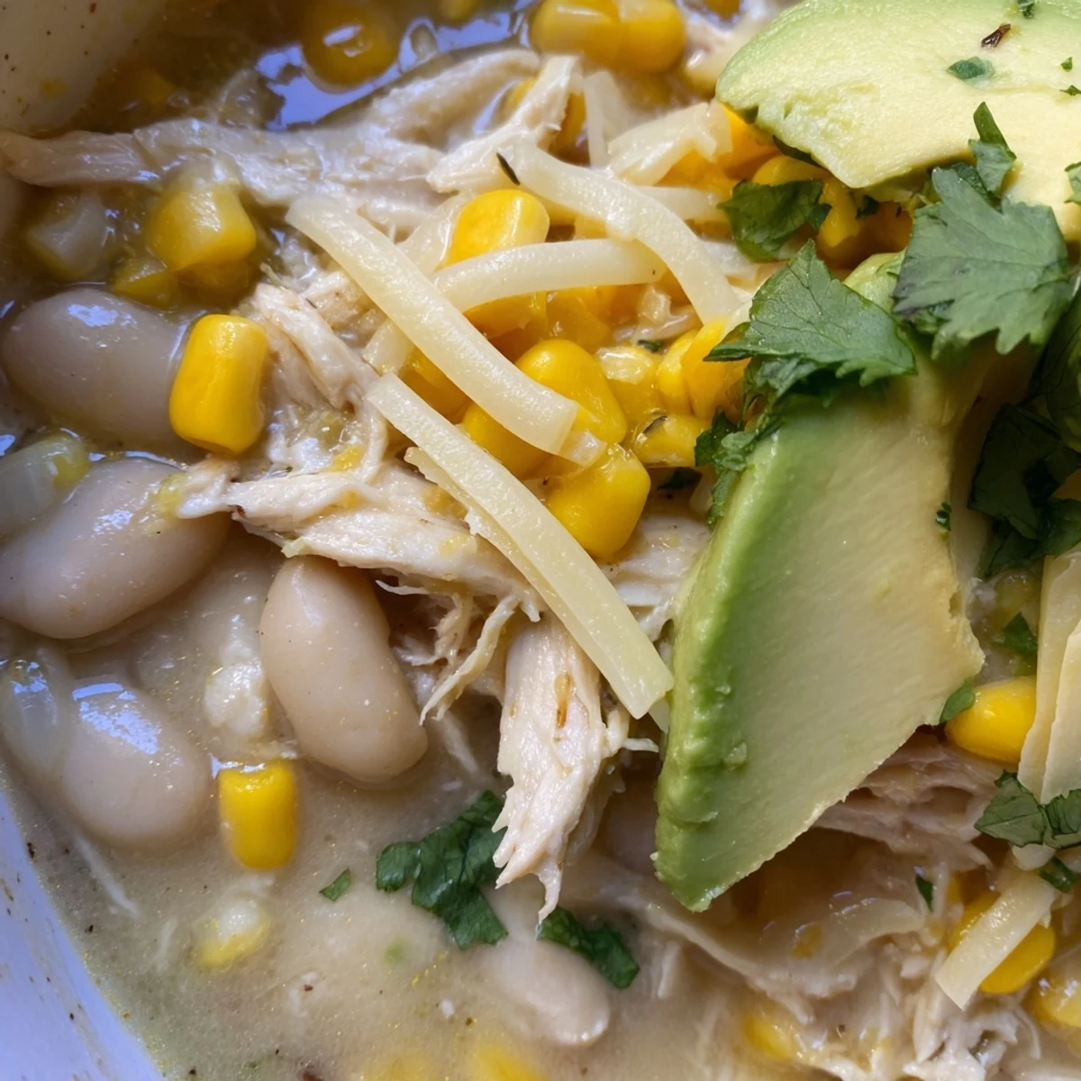 Steaming White Chicken Chili with corn and beans is served in a rustic bowl.