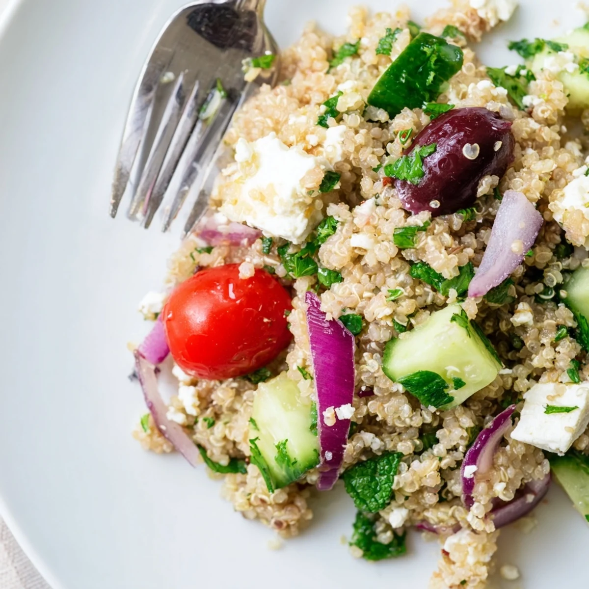A bowl of Mediterranean Quinoa Salad with cucumber, cherry tomatoes, and crumbled feta, tossed in a zesty lemon-herb dressing.