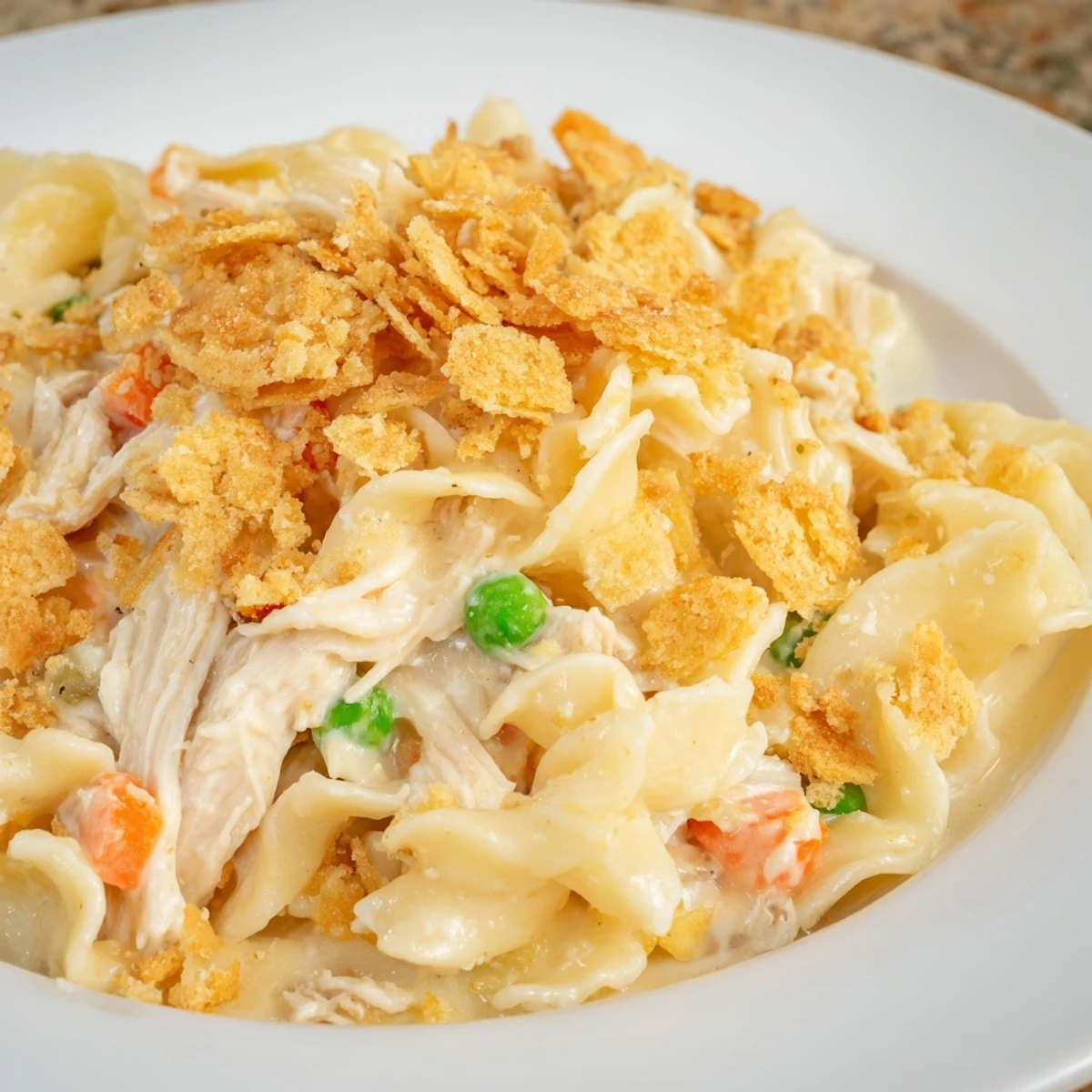 Golden-brown Chicken Noodle Casserole with Buttery Cracker Crumble bubbling in a 9x13 dish next to a green salad.