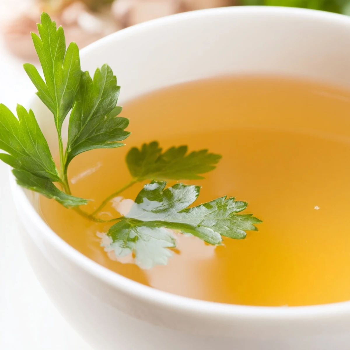 Steaming homemade vegetable broth with fresh herbs in a pot, featuring chopped carrots, celery, and aromatic thyme.