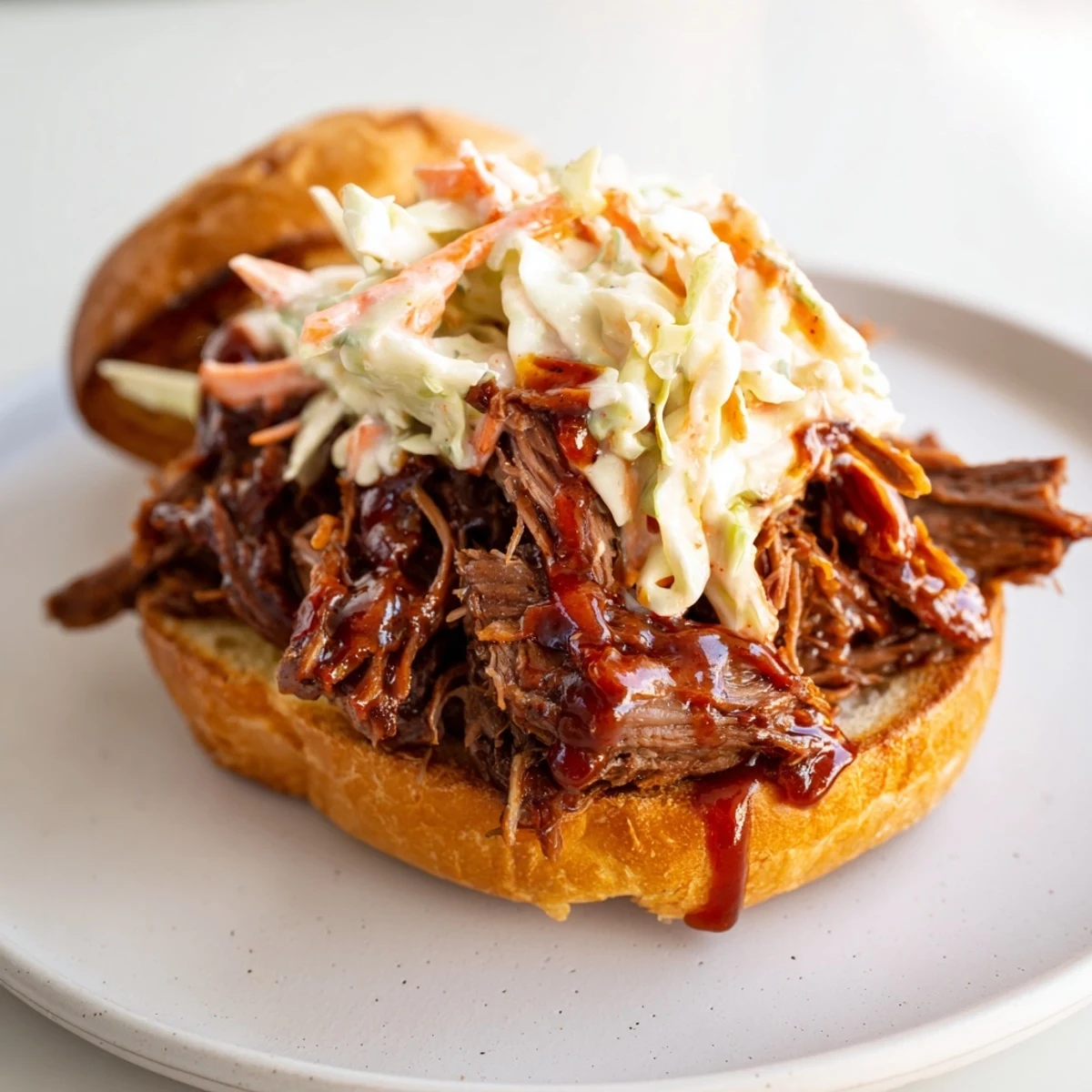Slow roasted pulled beef sandwiches piled high on a toasted brioche bun, topped with creamy coleslaw and barbecue sauce for a messy, delicious bite.