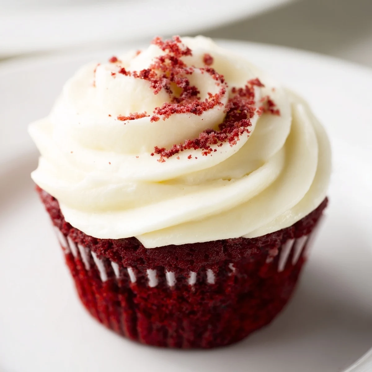 Twelve vibrant red velvet cupcakes lined up on a wire rack, each crowned with a fluffy swirl of cream cheese frosting.  