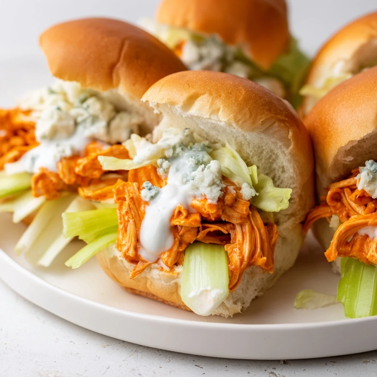 Easy buffalo chicken sliders with blue cheese sauce, drizzled with tangy buffalo sauce and garnished with fresh chives.