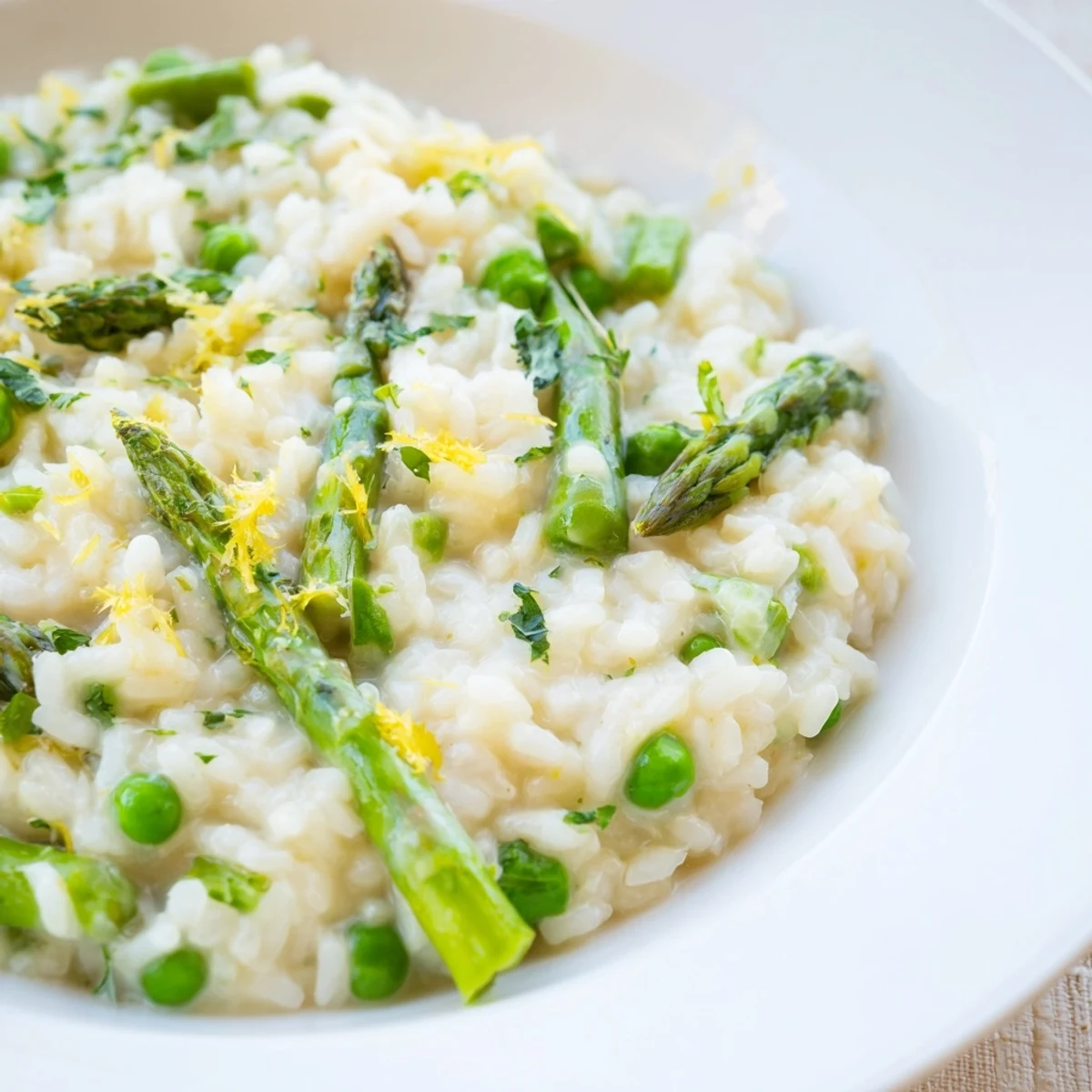 A vibrant bowl of creamy Spring Pea and Asparagus Risotto, garnished with fresh parsley and lemon zest.  