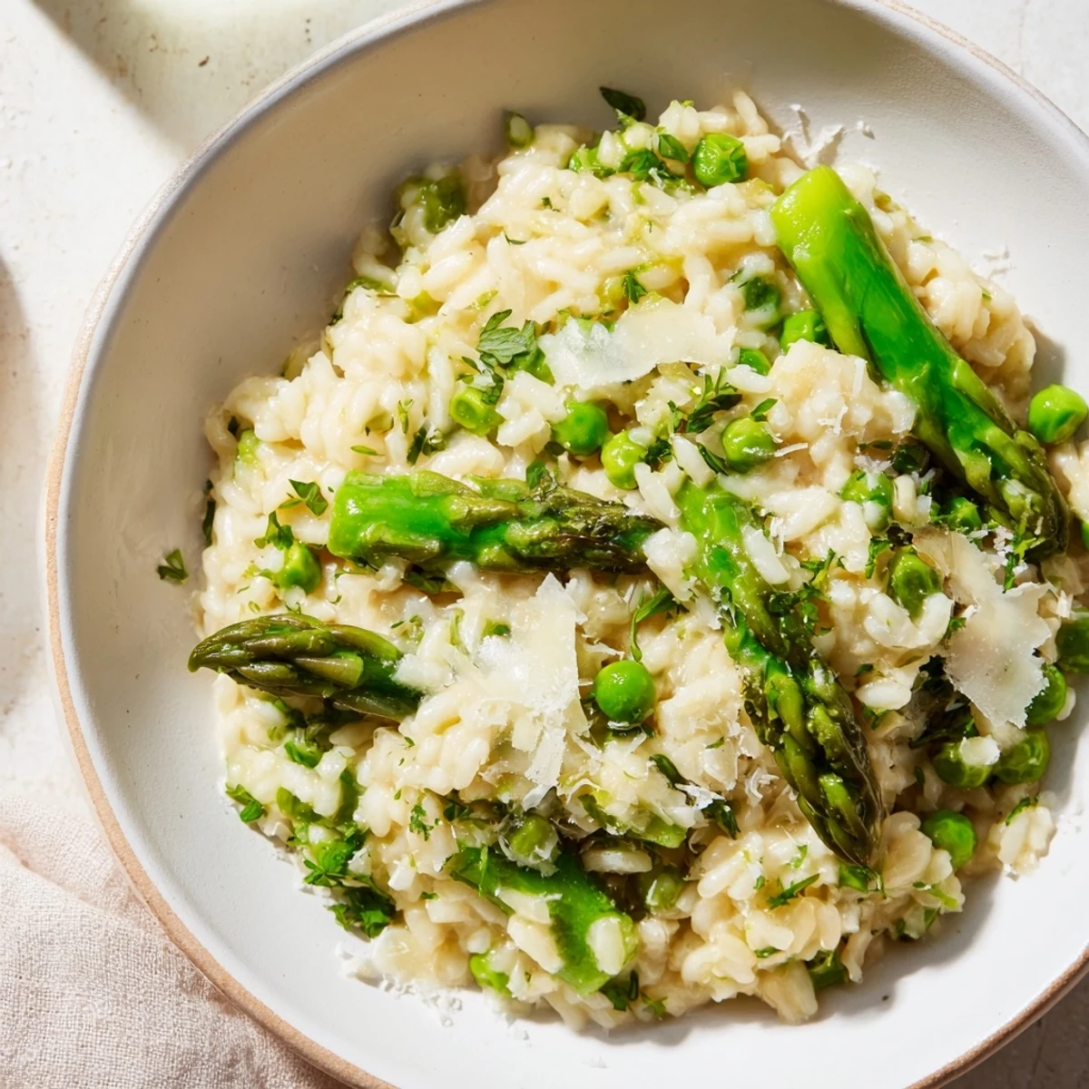 Close-up of a spoon scooping Spring Pea and Asparagus Risotto, revealing tender vegetables and a creamy texture.  