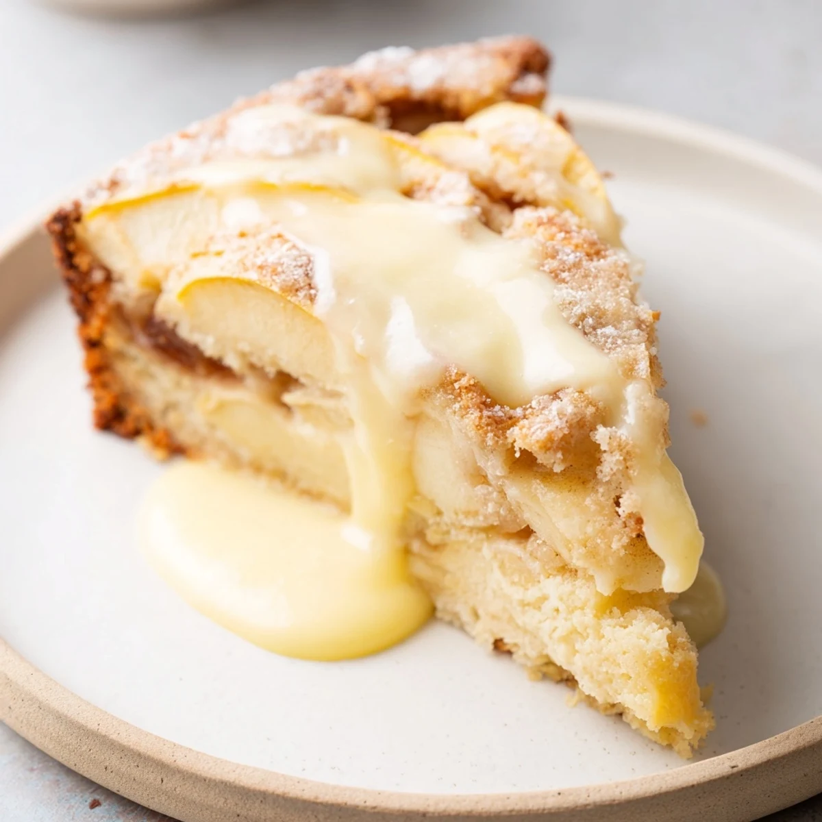 Irish Apple Cake with Custard rests on a rustic plate with a spoonful of vanilla custard for serving.