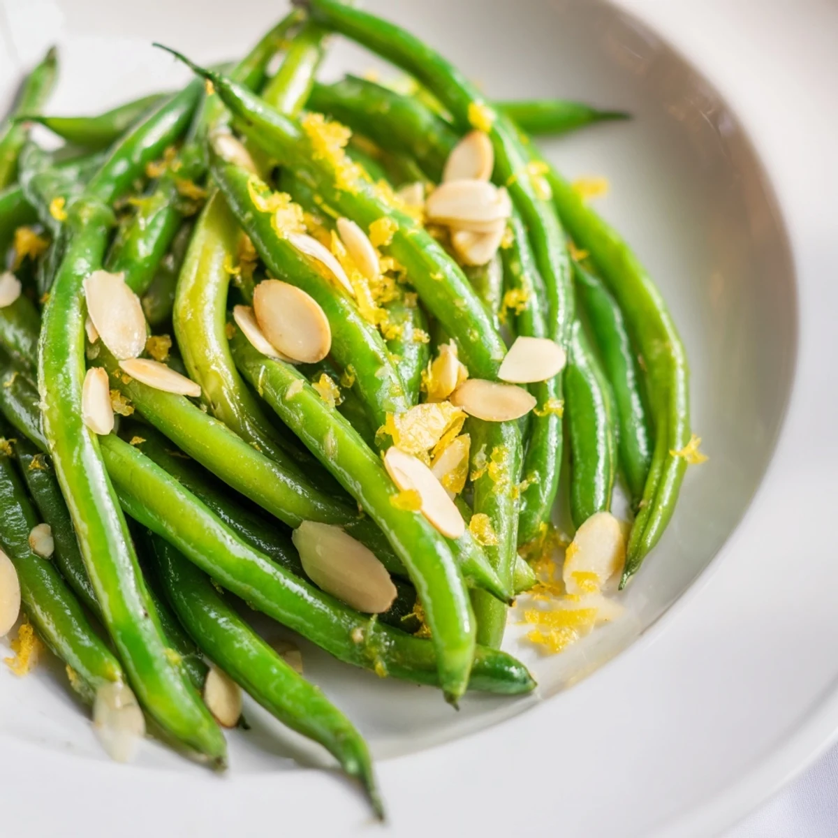 Vibrant green beans tossed in olive oil with garlic, lemon, and toasted almonds, ready to serve alongside grilled chicken.