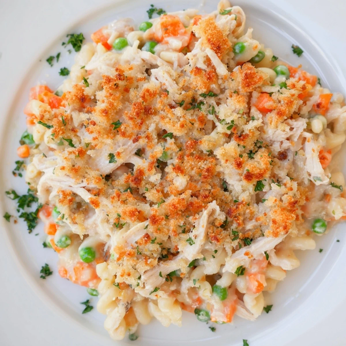 A spoon lifts creamy Chicken Noodle Casserole with Crumble, revealing tender chicken and noodles inside.