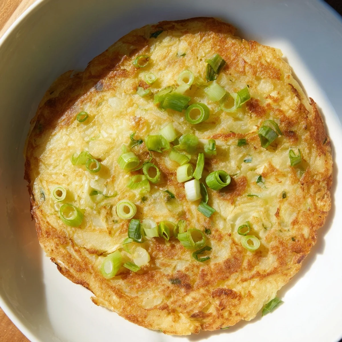 Close-up of warm Irish Potato Cakes with Scallions, garnished with green onion slices and a pat of butter.