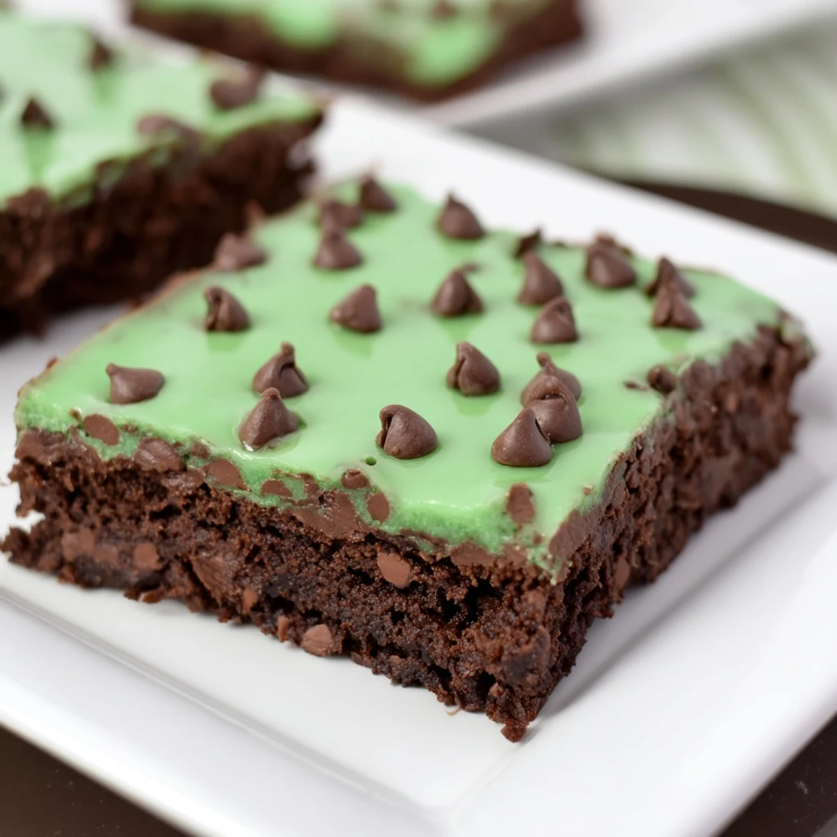 Freshly baked Green Mint Brownies with Chocolate Chips on a wooden board, garnished with mint leaves for serving.