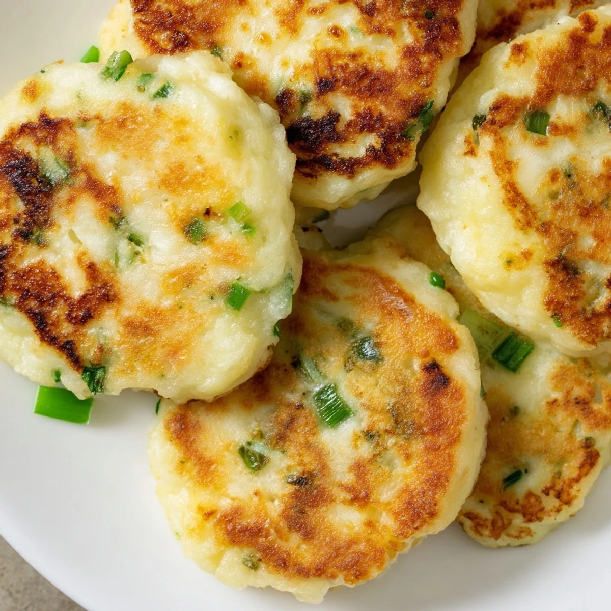 Two fluffy Irish Potato Cakes with Scallions show fresh green flecks and a crisp, golden-brown exterior.