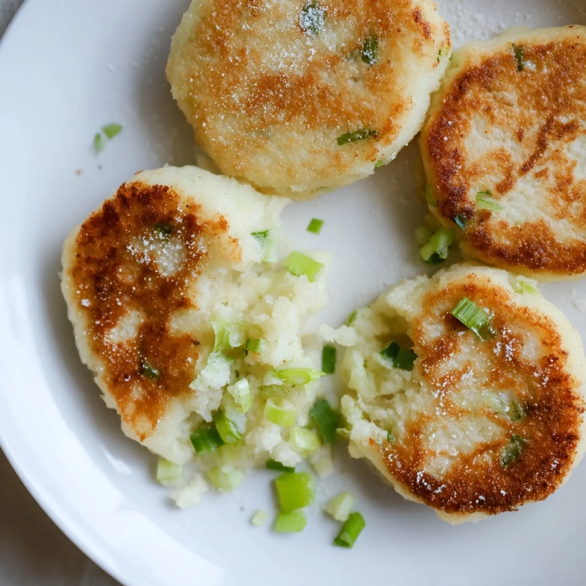 Freshly cooked Irish Potato Cakes with Scallions rest on a rustic plate with melting butter.