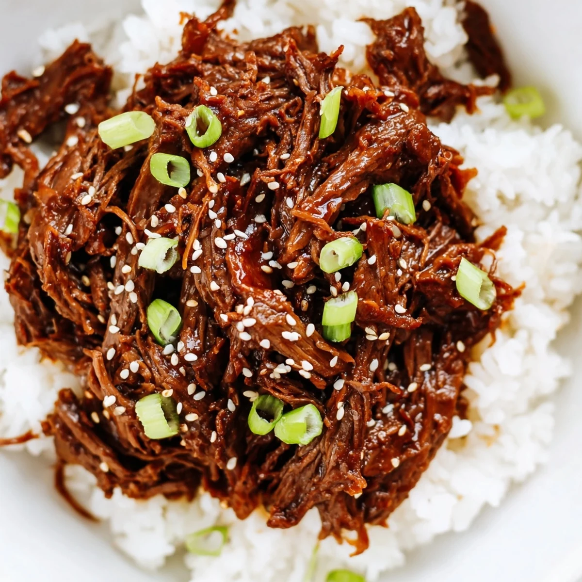 Steaming bowl of Slow Cooker Korean Beef alongside kimchi and steamed broccoli, finished with sliced green onions and red chili garnish.