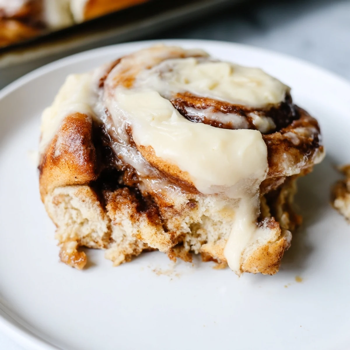 A warm Keto Cinnamon Bun with creamy icing on a rustic wooden board for breakfast.