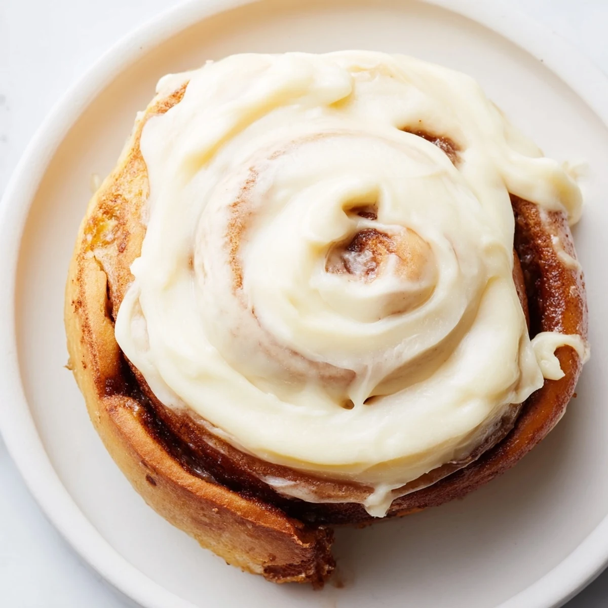 Stack of Keto Cinnamon Buns on a white plate with a cup of black coffee.