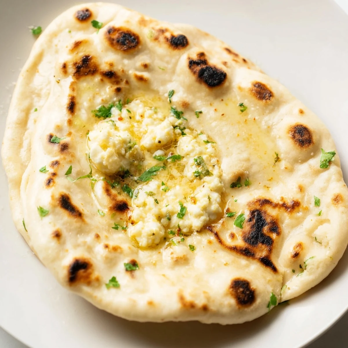 Soft, pillowy Cottage Cheese Garlic Naan brushed with herb butter, served warm alongside a flavorful curry dish.