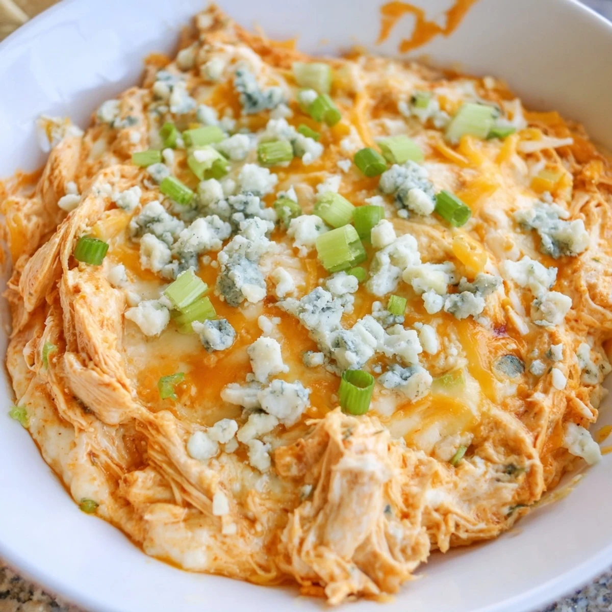 Creamy Keto Buffalo Chicken Dip in a baking dish, golden bubbly cheese topping with green onion garnish for game day.
