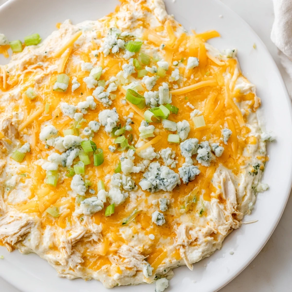 Keto Buffalo Chicken Dip cooling on a plate, shredded chicken and melted cheese in a creamy buffalo sauce.