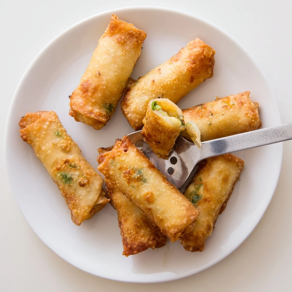 These golden Mini Jalapeño Popper Egg Rolls are cooling on a wire rack, highlighting their crunchy texture and creamy filling.