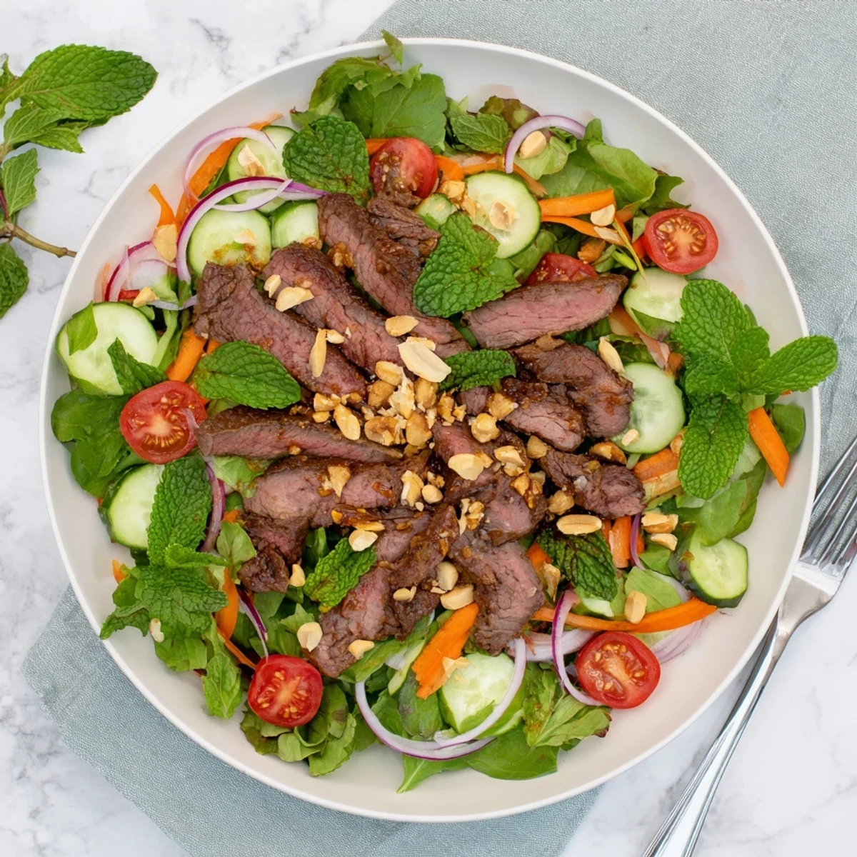 A close-up of Vietnamese Beef and Watercress Salad shows tender marinated beef slices and fresh greens tossed in a tangy dressing.