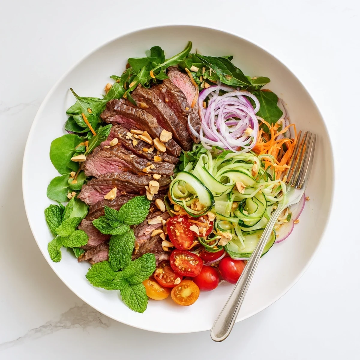 A vibrant Vietnamese Beef and Watercress Salad served on a plate with juicy tomatoes, fresh herbs, and a drizzle of dressing.