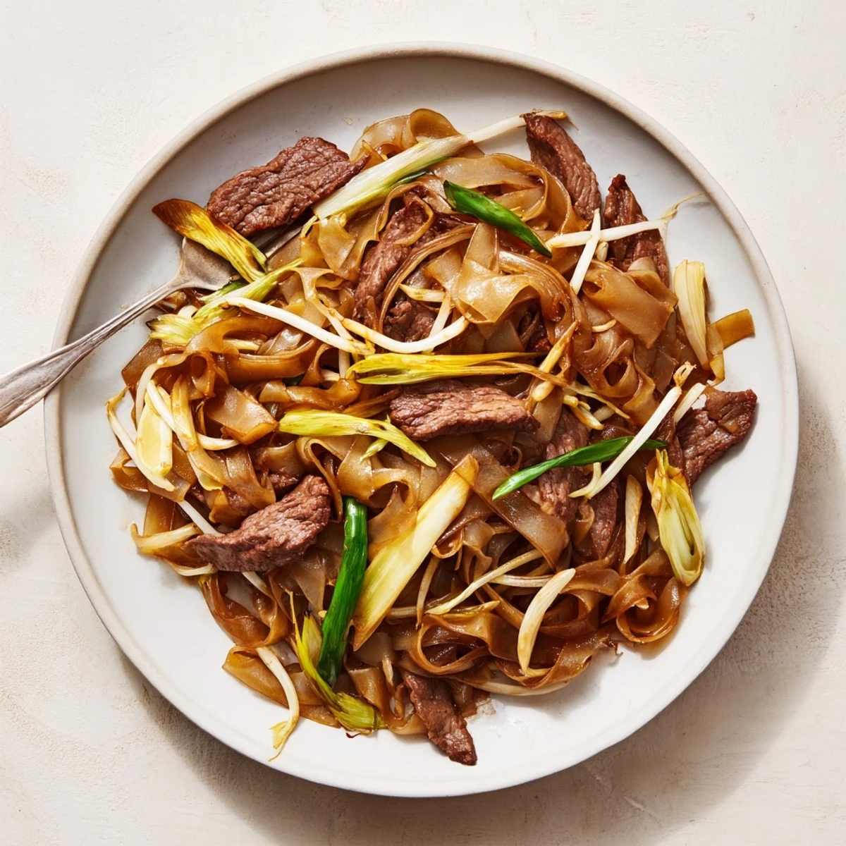 Beef Chow Fun served hot with bean sprouts and green onions on a wooden platter for family style dinner.