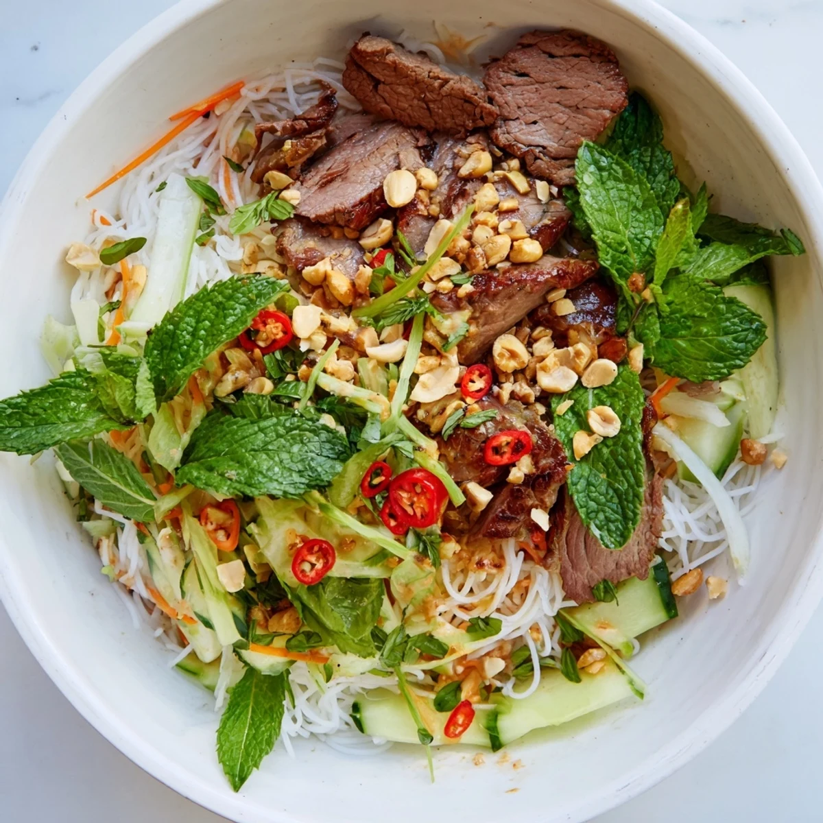 Overhead view of Bun Bo Xao, a Vietnamese noodle salad with vibrant herbs, sprouts, and a tangy dressing.