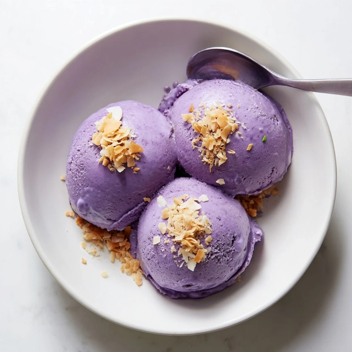 Rich and sweet ube ice cream in a ceramic bowl, garnished with a drizzle of condensed milk for a Filipino treat.