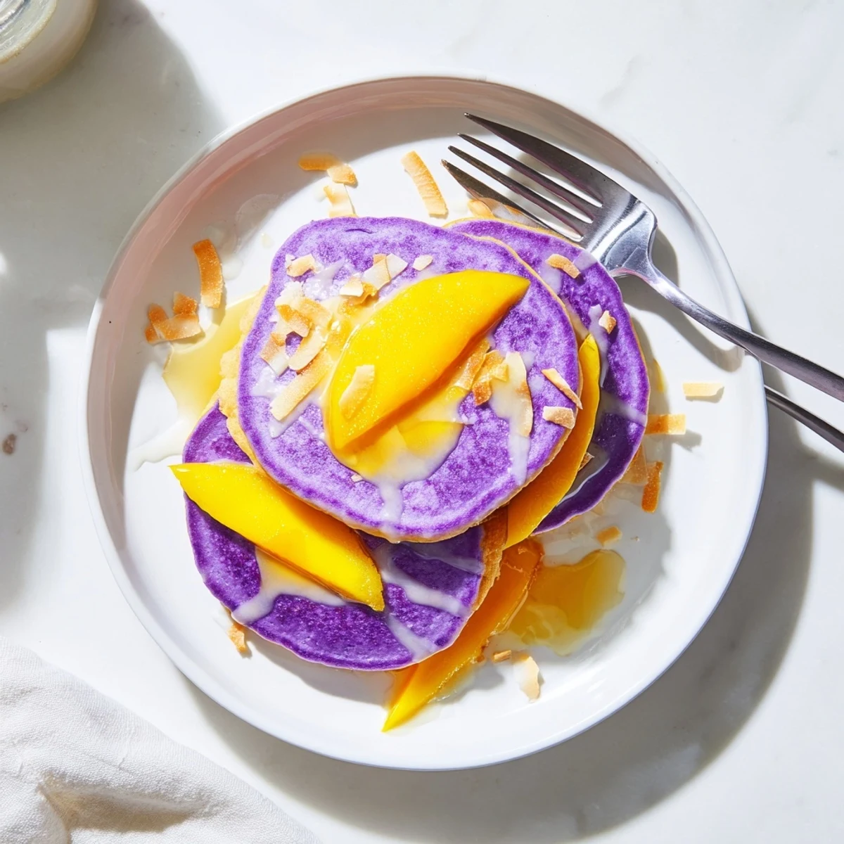Fluffy Ube Mochi Pancakes stacked high with a drizzle of sweetened condensed milk for a sweet Filipino-inspired breakfast.