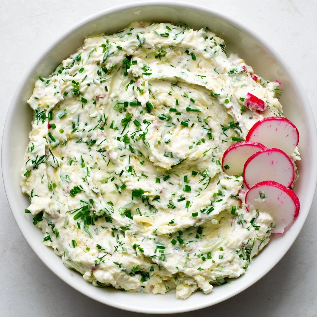 A close-up of the Simple Easter Herb Cheese Dip garnished with fresh dill and chives, served with crunchy vegetable sticks.
