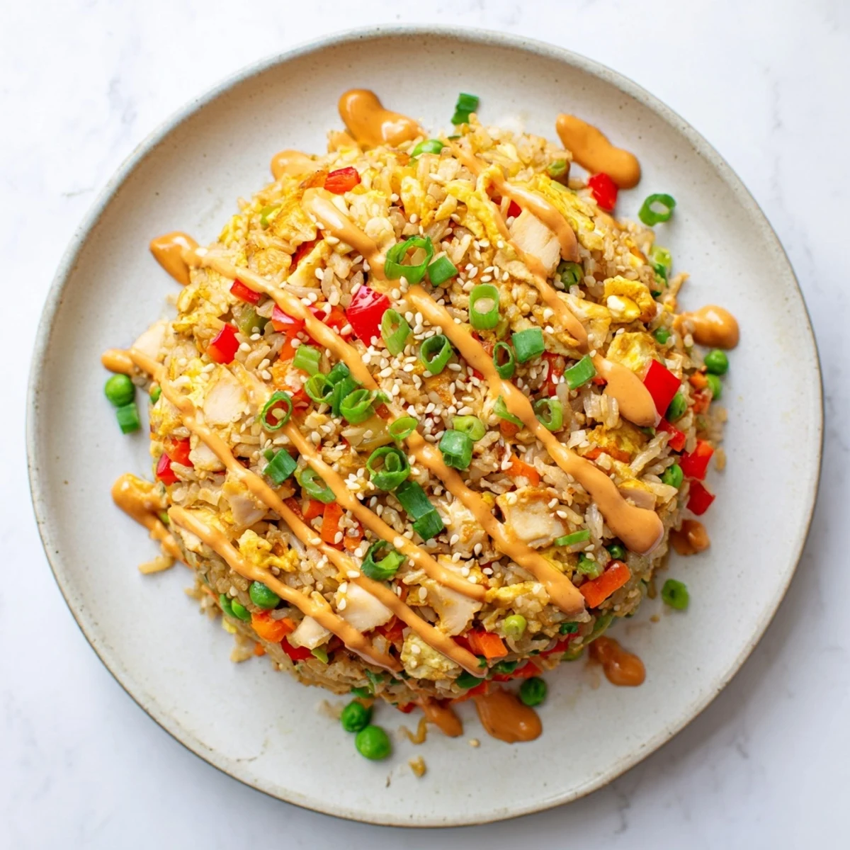 A bowl of Bang Bang Fried Rice with creamy sauce drizzled over crispy veggies and tender chicken.
