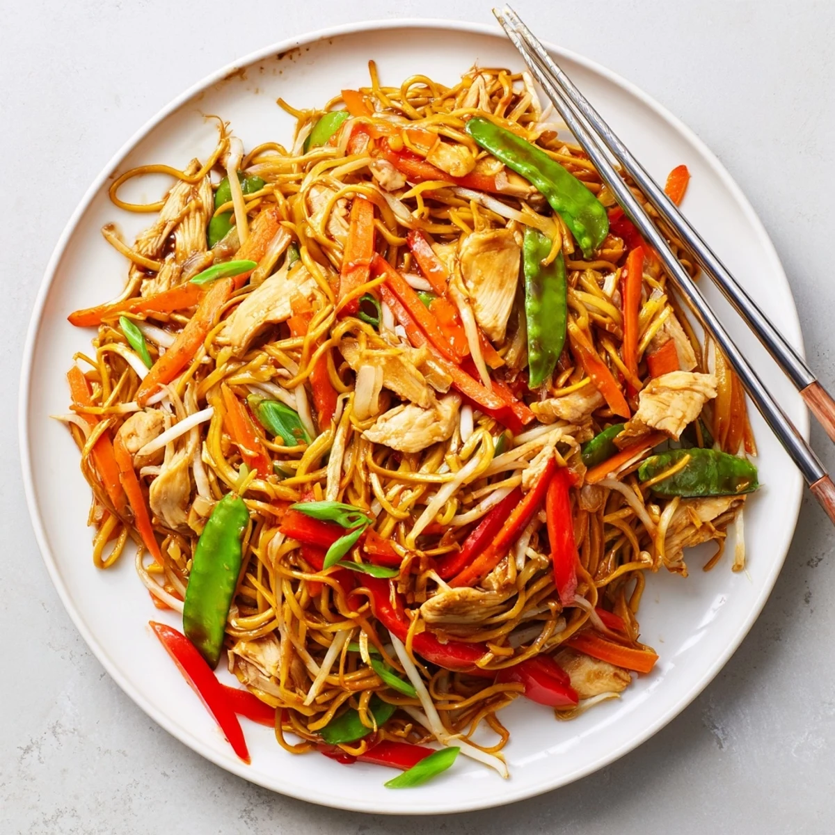 Family-style Chicken Chow Mein in a wok, loaded with chicken, crunchy veggies, and savory sauce for a quick dinner.