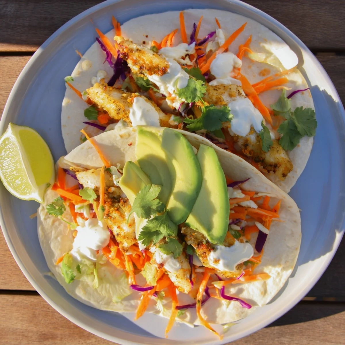 Easy As Aussie Barra Tacos, garnished with creamy dollops of sour cream and chopped coriander, served with lime wedges.  