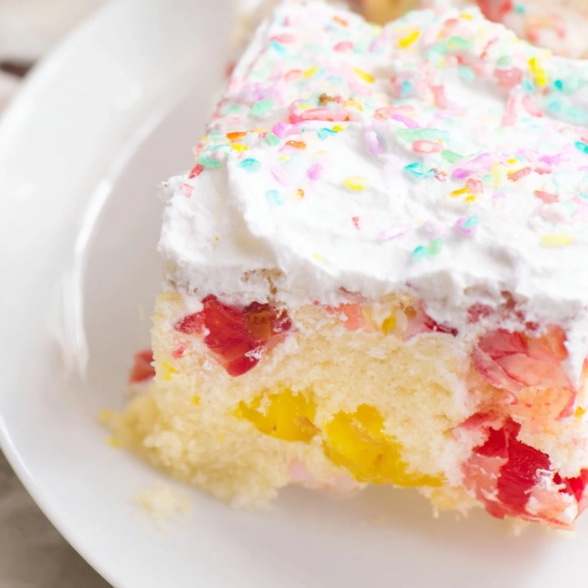 Close-up of Easter Poke Cake with Vanilla Gelatin and Fruity Topping, showing gelatin pooling in the holes and colorful toppings for a festive look.