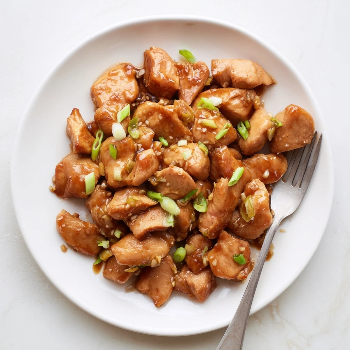 Easy sweet Mongolian chicken plated with green onions over steamed white rice