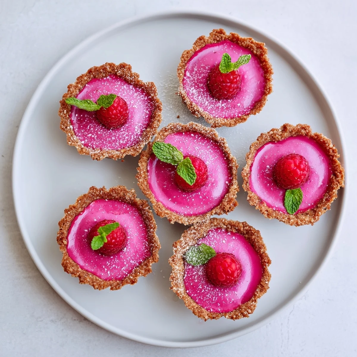 Vegan raspberry curd tarts feature vibrant pink filling nestled in buttery golden pastry crust