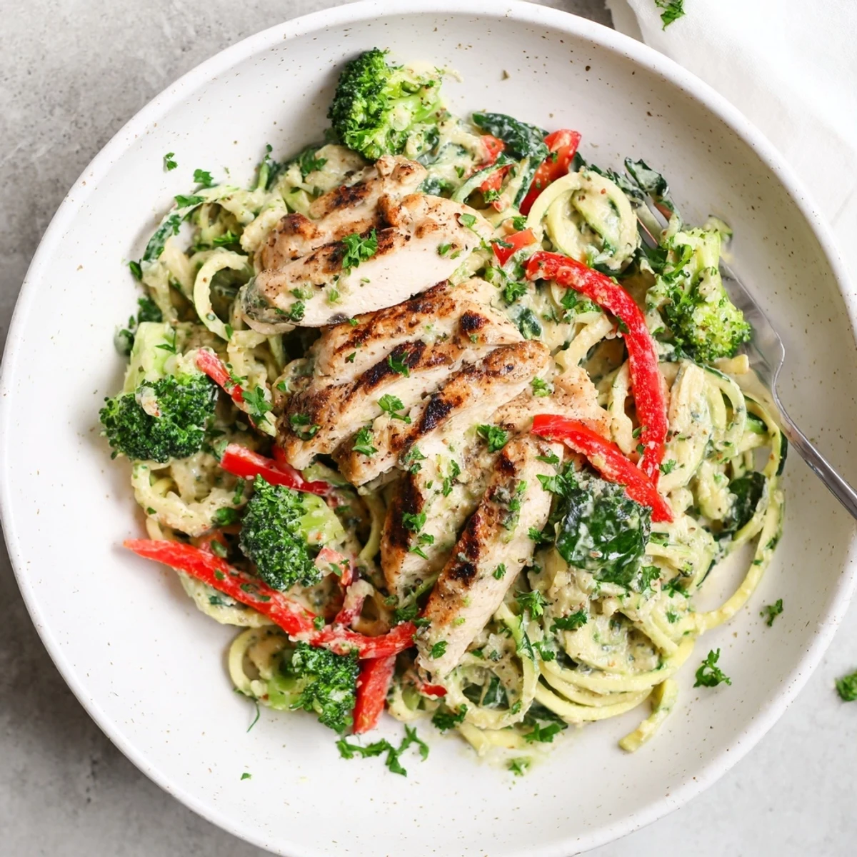 Golden chicken breast slices served over spiralized zucchini noodles in rich Parmesan cream sauce.