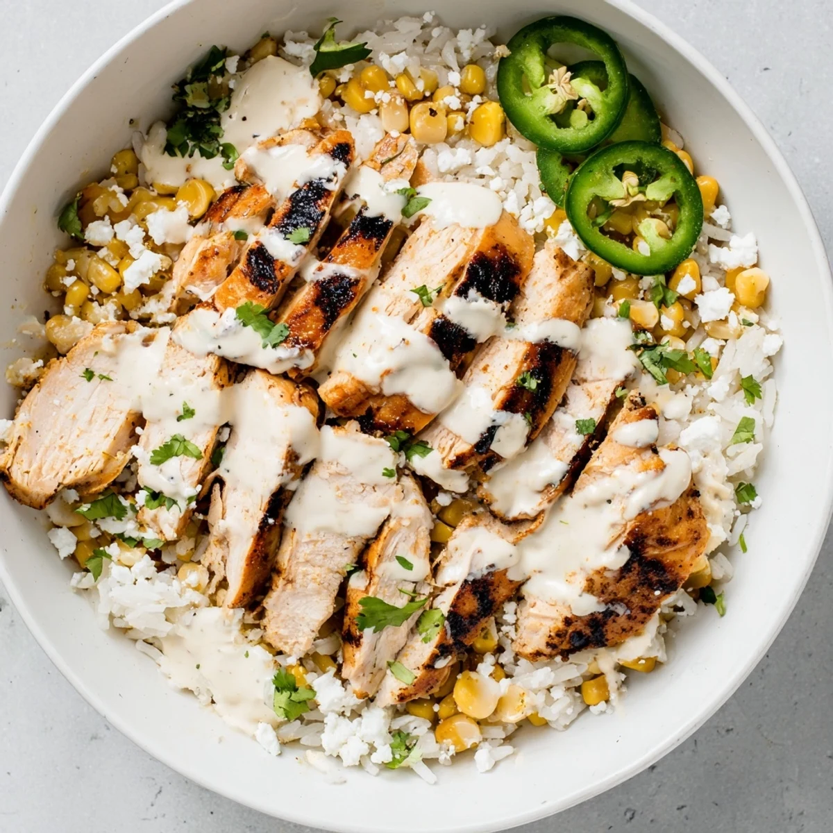 Golden grilled chicken nestled over fluffy white rice topped with charred street corn and tangy lime crema drizzle