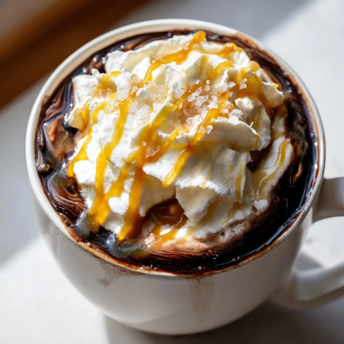 Rich homemade salted caramel hot chocolate garnished with flaky sea salt and vanilla foam