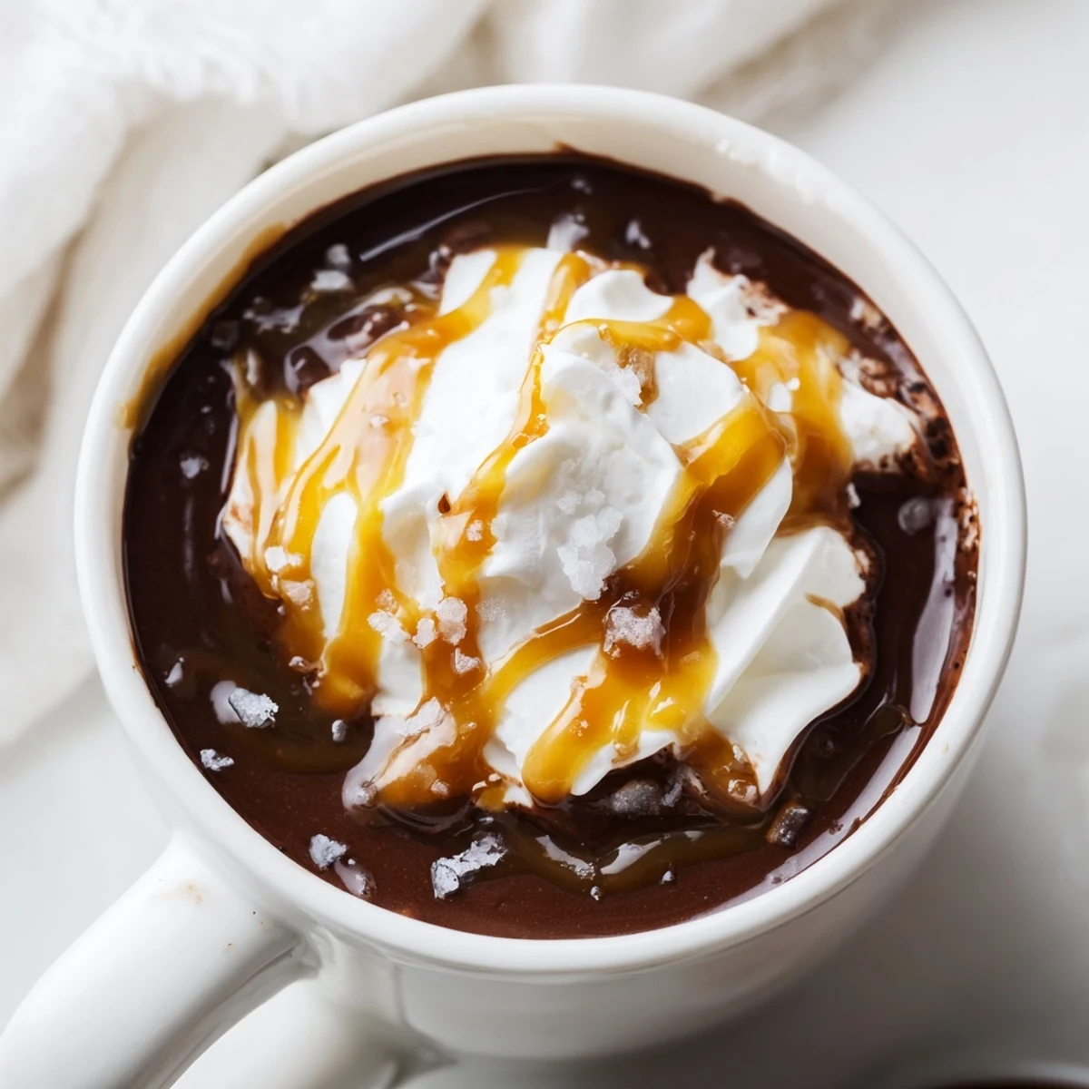 Steaming mug of salted caramel hot chocolate with melted chocolate and caramel swirls