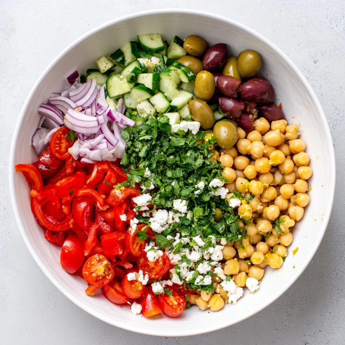 Fresh Mediterranean chickpea salad featuring olives, tomatoes, cucumber and bright parsley garnish