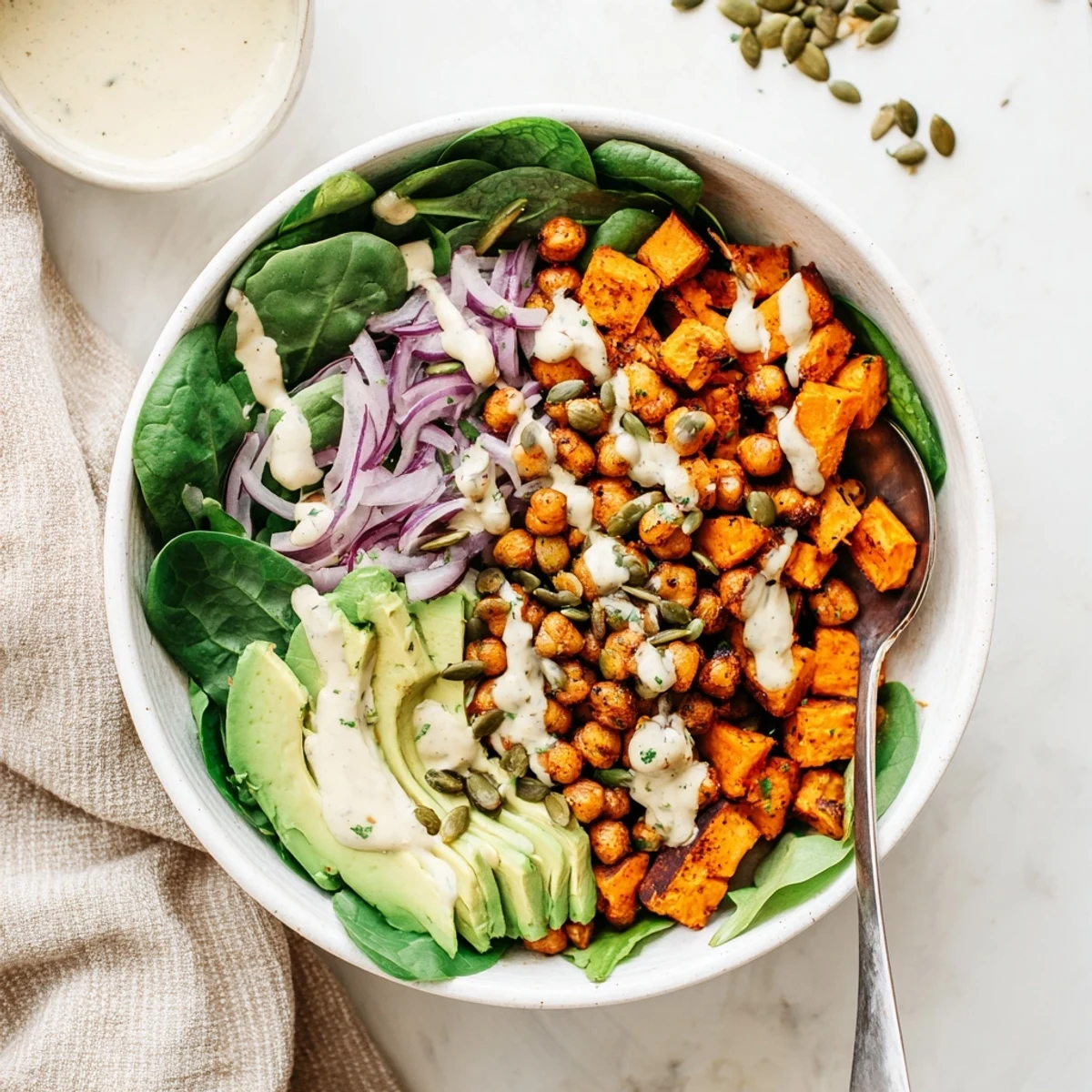 Colorful roasted sweet potato and chickpea bowls drizzled with creamy tahini dressing over fresh greens