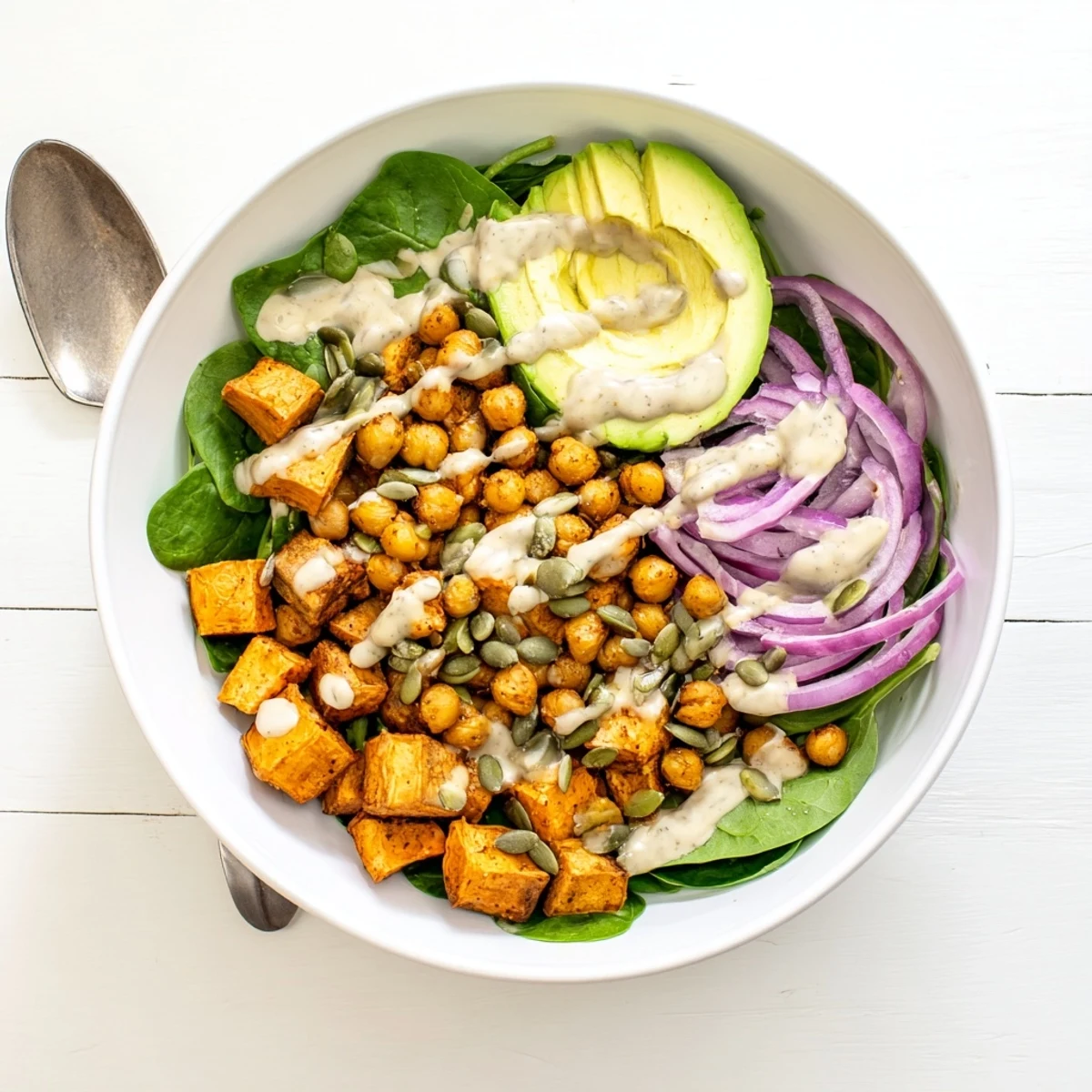 Golden caramelized sweet potato and crispy chickpea grain bowl topped with avocado and zesty tahini sauce
