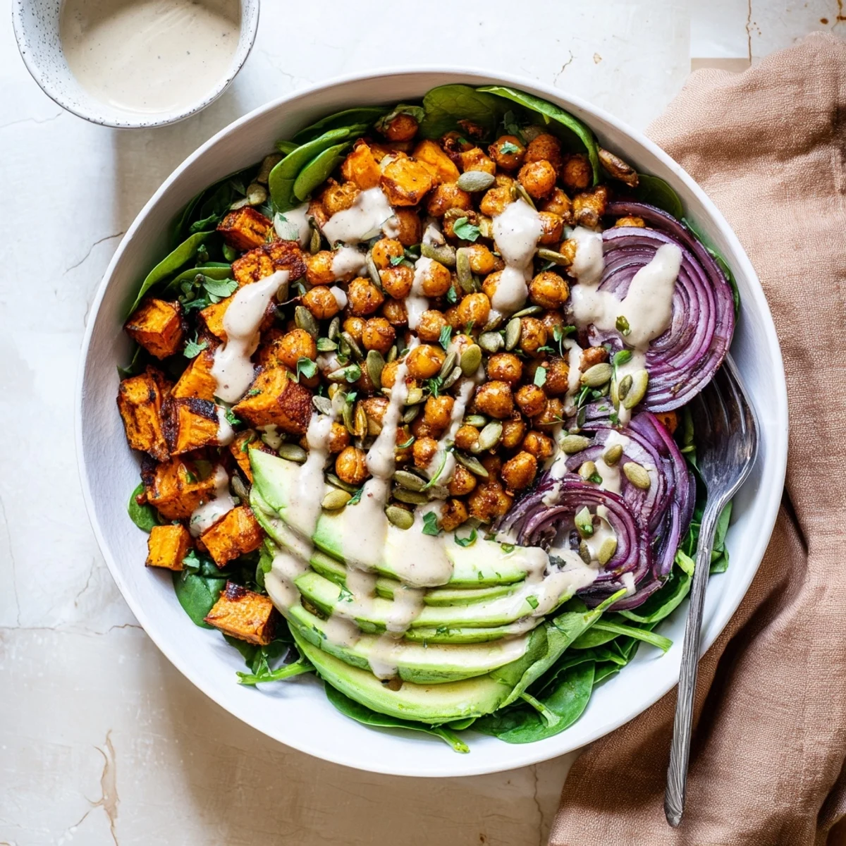 Wholesome vegetarian meal featuring roasted sweet potatoes, spiced chickpeas, and baby spinach with nutty dressing