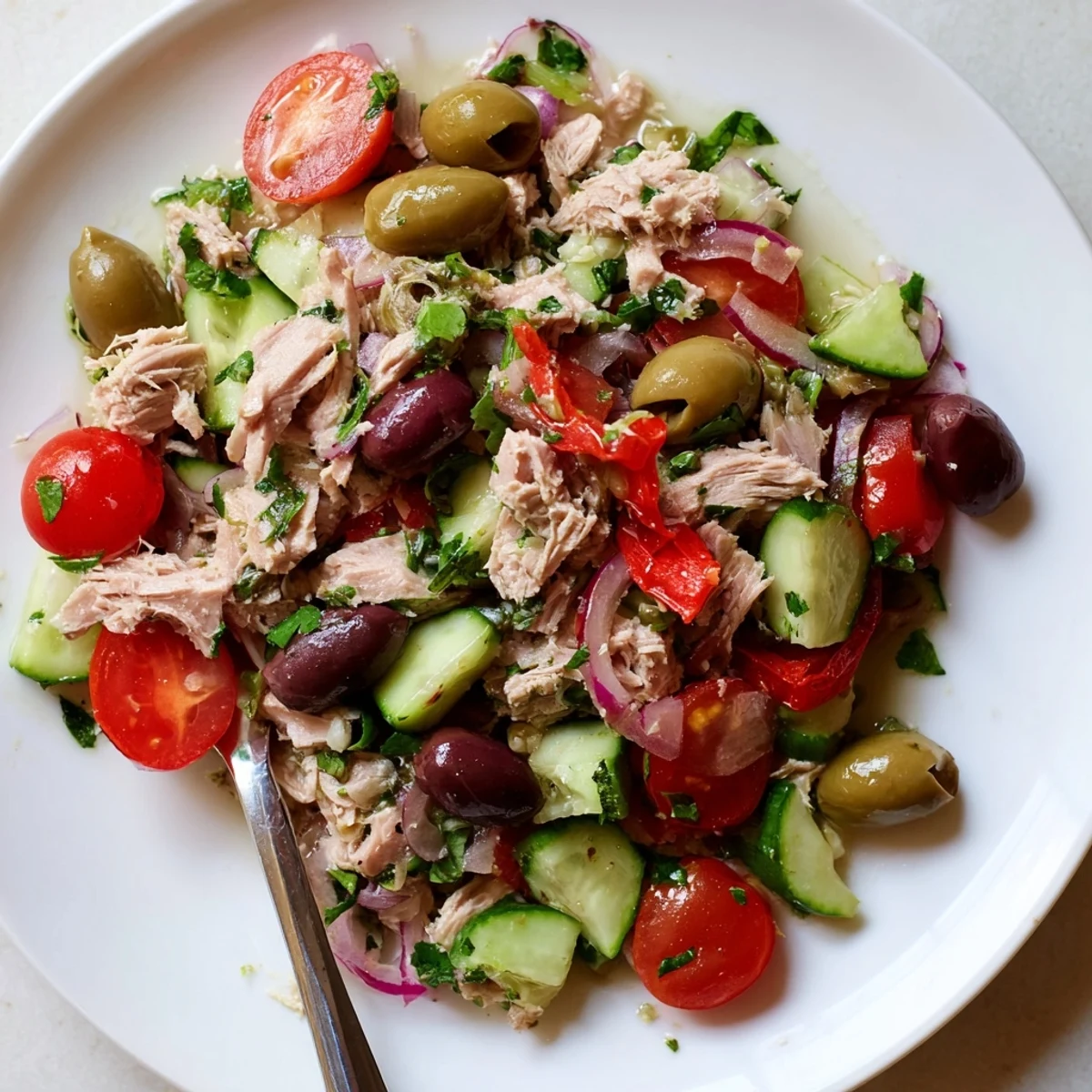 Colorful Mediterranean tuna salad bowl loaded with fresh vegetables, olives, and lemon dressing