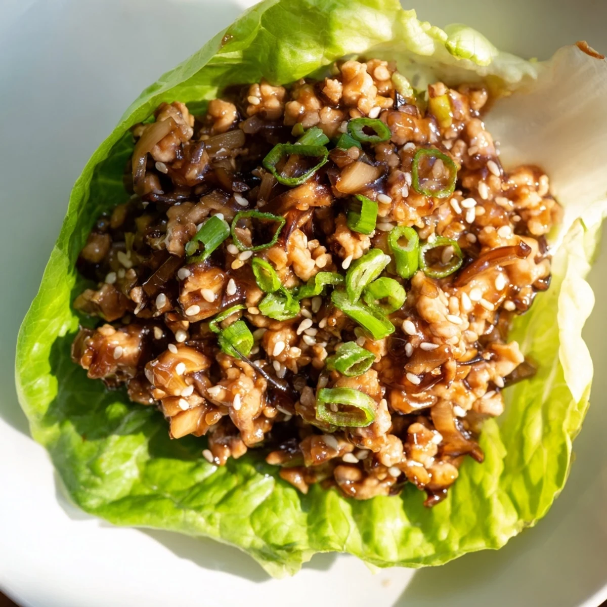 Golden brown ground chicken mixture with mushrooms and water chestnuts spooned into crisp butter lettuce cups