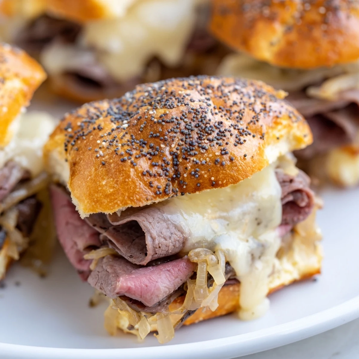 Small bowl of rich au jus beside warm French dip sliders ready for dipping