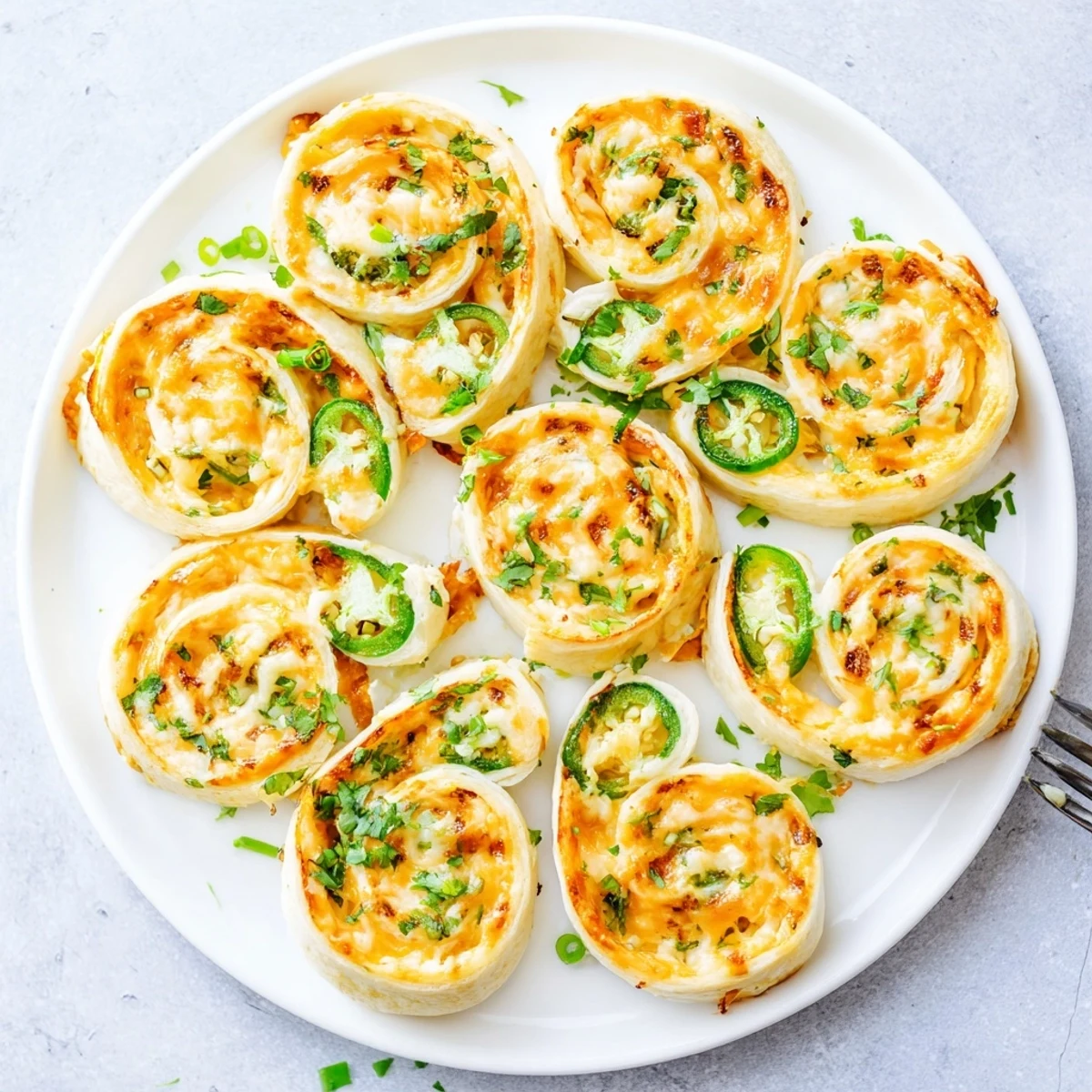 Golden baked easy jalapeno popper pinwheels with melted cheddar cheese and fresh green onion bits