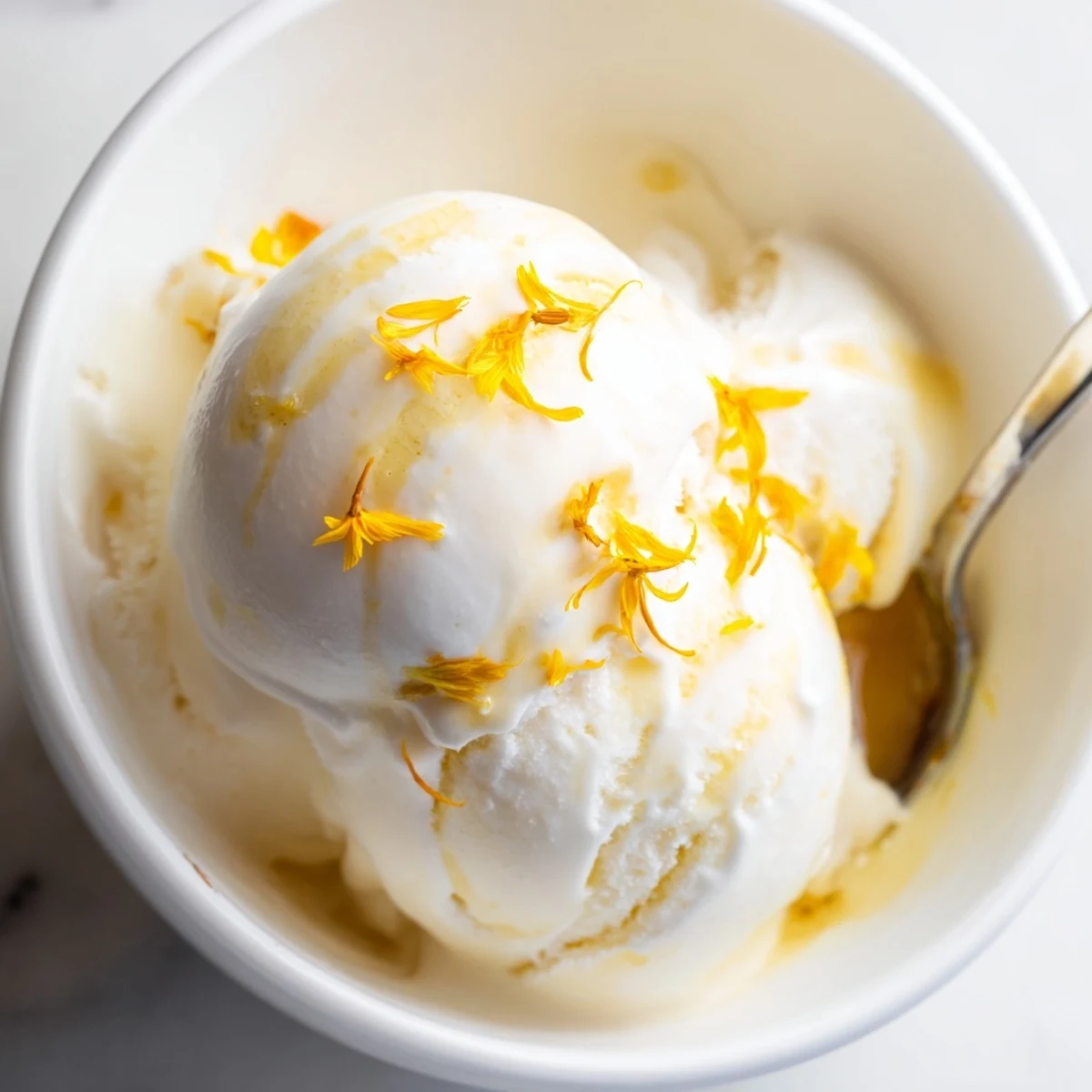Velvety homemade dandelion honey ice cream garnished with fresh edible dandelion flowers