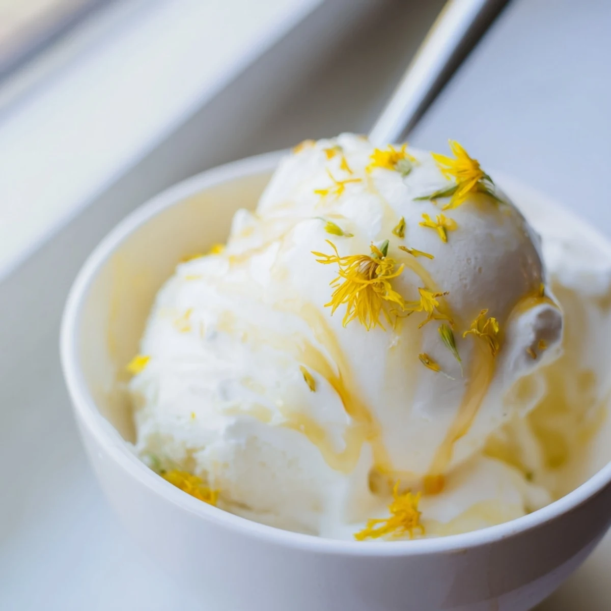 Rich floral dandelion honey ice cream swirled with extra honey on a dessert plate